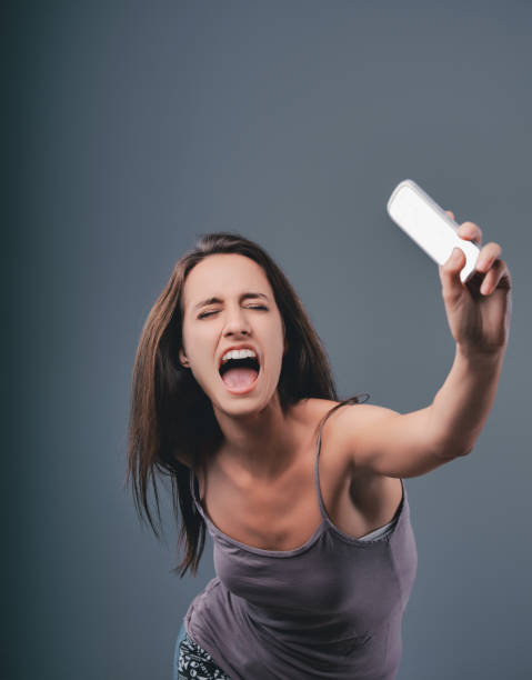 istock Young woman shouting at smartphone on grey background 2170318020