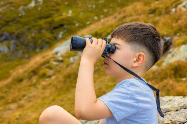 istock kid in mountains watching with binoculars.beautiful breathtaking landscape with hills and grass.child boy against lake.summer time,vacation mood.preschooler is traveling by car with parents. 2170323401