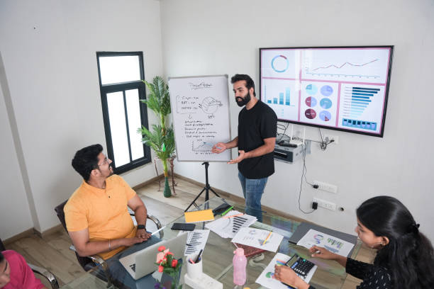 istock young indian man entrepreneur present business financial data on whiteboard at the workplace to colleagues for a start-up project. sales, analysis and strategy, Entrepreneurship 2170334851