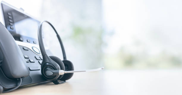 istock Headset headphones telephone with microphone on desk in support and customer service help desk call center background 2170334896
