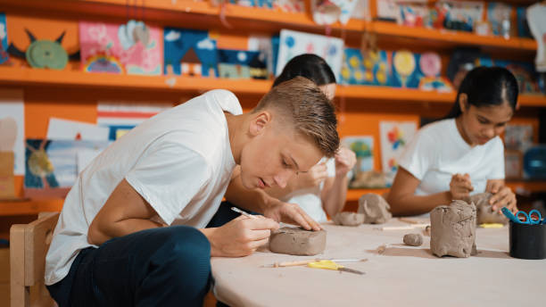 istock Teenager using carving tool working at clay at pottery workshop. Edification. 2170337940