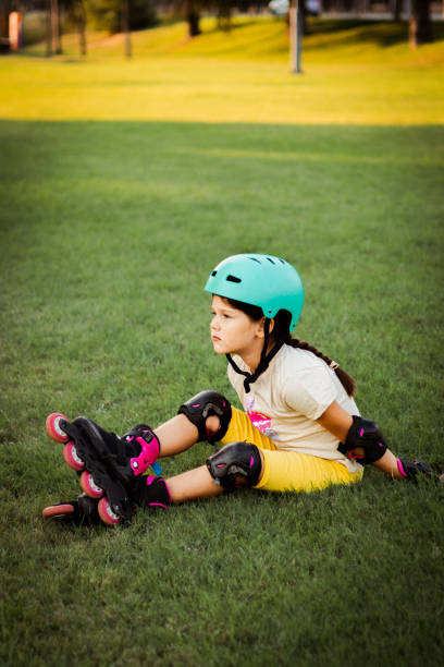istock Beautiful playful school girl with protective equipment and helmet on inline rollerblade skates in public park near the corporate building. 2170340308