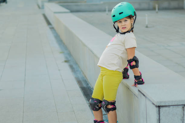 istock Beautiful playful school girl with protective equipment and helmet on inline rollerblade skates in public park near the corporate building. 2170341867