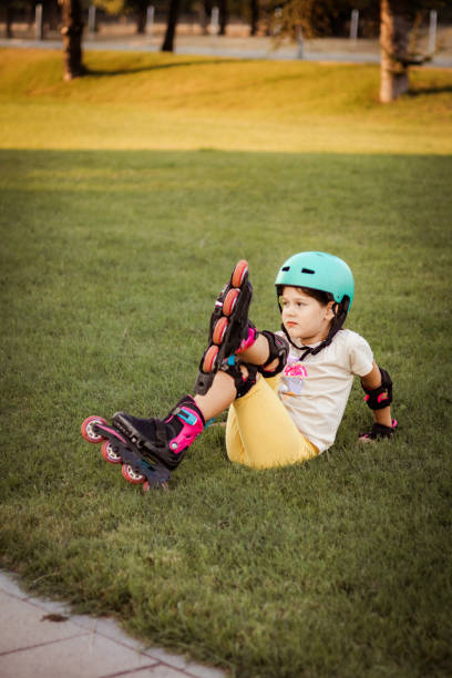istock Beautiful playful school girl with protective equipment and helmet on inline rollerblade skates in public park near the corporate building. 2170342079