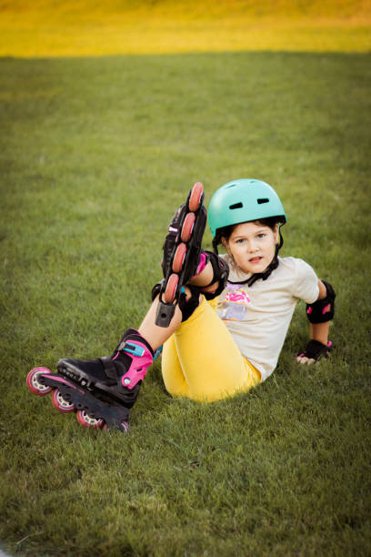 istock Beautiful playful school girl with protective equipment and helmet on inline rollerblade skates in public park near the corporate building. 2170342251