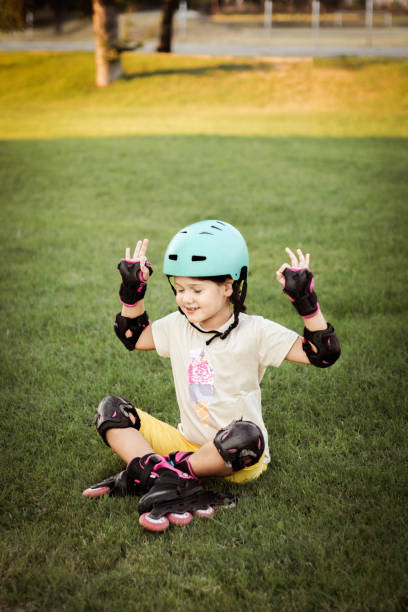 istock Beautiful playful school girl with protective equipment and helmet on inline rollerblade skates in public park near the corporate building. 2170342343
