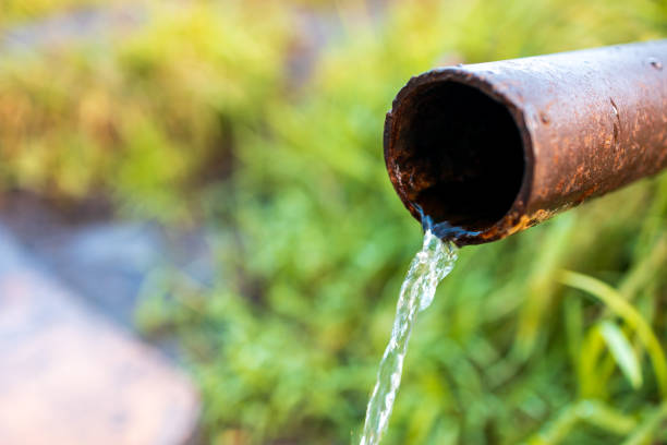 istock water flows in a thin stream from the pipe, the background is grass 2170344291