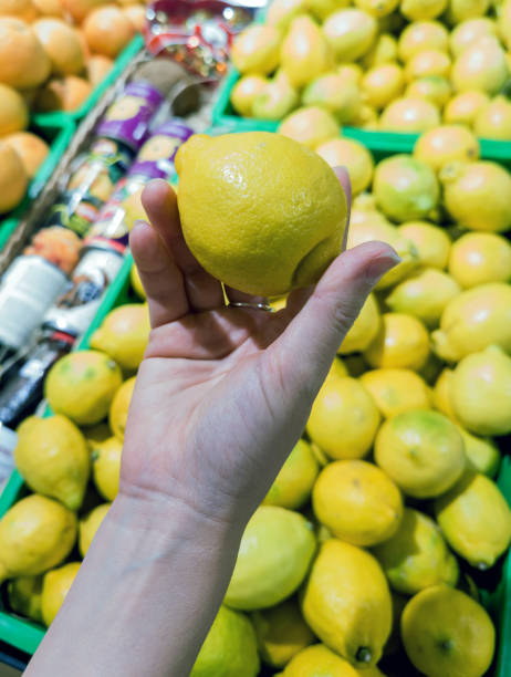 istock hand selecting a ripe lemon in a grocery store 2170345010