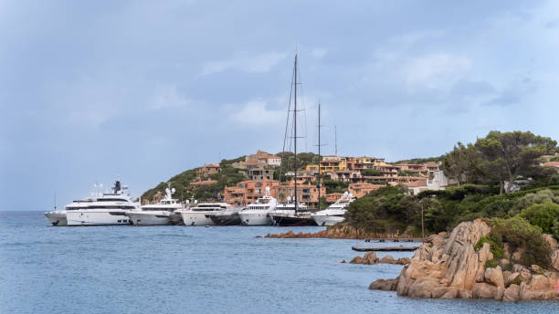 Landscape of the coast of Porto Cervo village on the Emerald Coast of Sardinia island, with large luxury yachts and a very natural environment with vegetation and residential buildings Landscape of the coast of Porto Cervo village on the Emerald Coast of Sardinia island, with large luxury yachts and a very natural environment with vegetation and residential buildings. Sardinian tourism concept costa esmeralda stock pictures, royalty-free photos & images