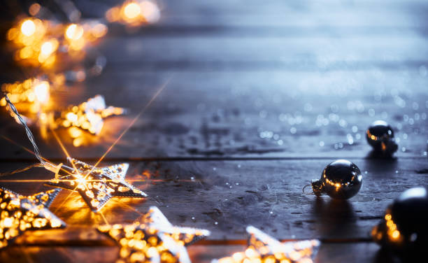 Festive Christmas decorations with glowing star-shaped string lights and silver baubles on rustic wooden table