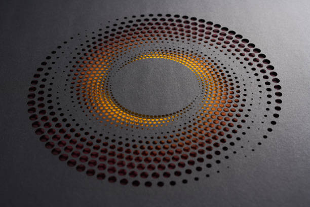 istock Circular paper cutout artwork with layered dot pattern and warm orange backlighting on dark surface 2170348742