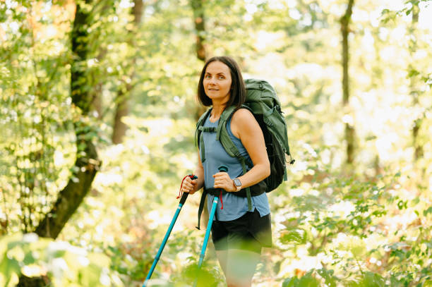 istock A woman is happily hiking through the lush greenery while carrying her backpack and using her trekking poles 2170351248