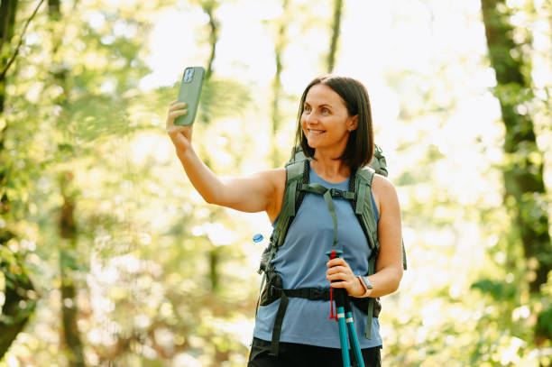 istock A joyful hiker happily captures a breathtaking selfie while standing among vibrant, sunlit trees in a lush forest 2170351398