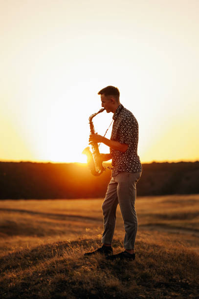 istock A talented musician skillfully plays the saxophone against a breathtaking sunset backdrop in a peaceful landscape 2170351411