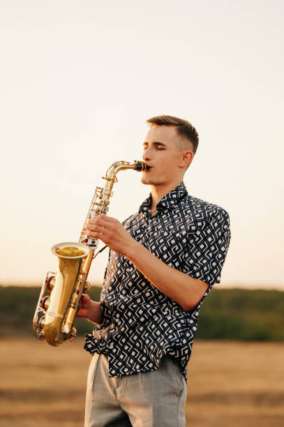 istock In a tranquil outdoor setting during a beautiful sunset, a young man skillfully plays his saxophone with deep emotion 2170351420