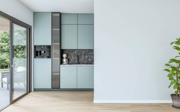istock Modern powder blue kitchen with large windows (garden view) in the background and a potted plant (ficus) in front of a white blank wall in the foreground 2170351940