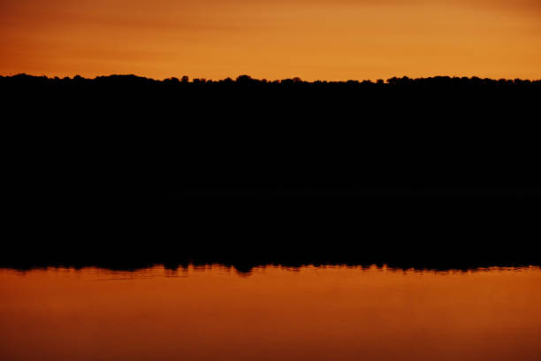 A stunning sunset casts a warm glow, mirrored on still waters, ideal for nature lovers seeking peace and beauty.