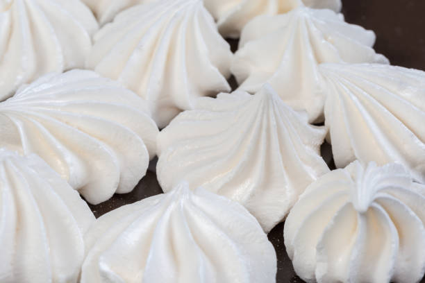 Meringue cookies on a brown dish, fragment close-up in selective focus