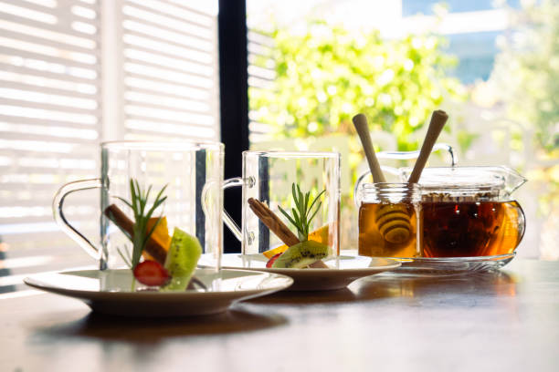Hot organic black tea with fresh lemon. A beautiful mug with a gold edging on a background of dessert.