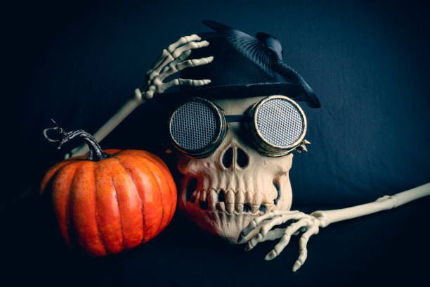 A close up of a skull and pumpkin Halloween decoration on a black background.