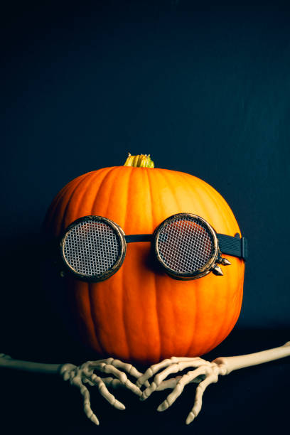 A pumpkin dressed for Halloween with steam punk glasses and skeleton hands.