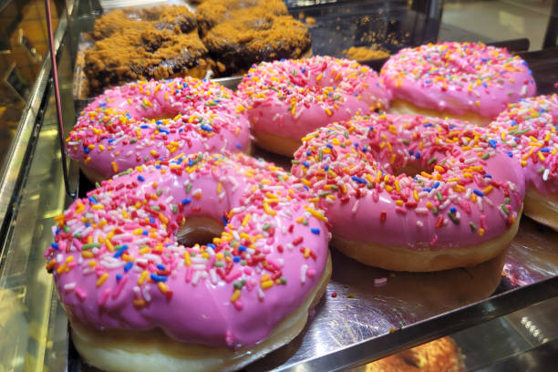 istock Sweet pink donuts with sprinkles displayed on a shelf in a bakery 2170363985