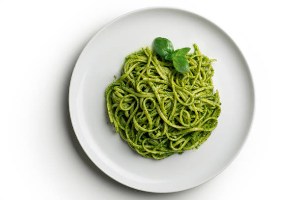 Top view of White plate with linguine with Genoese pesto sauce with basil leaves on white background