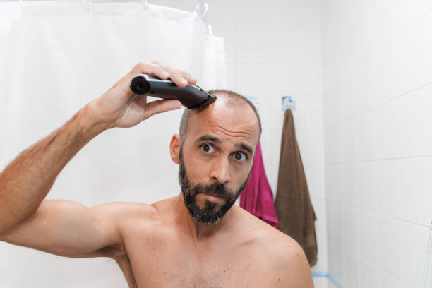 A man is shaving his head with a razor