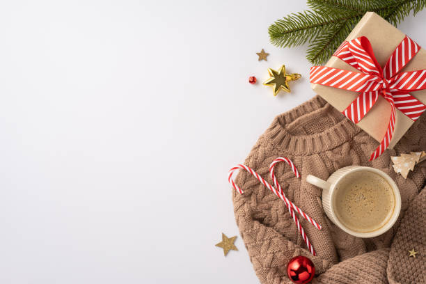 istock Warm and inviting winter setting featuring a wrapped gift, hot beverage, candy canes, and festive ornaments on a knit sweater 2170375074
