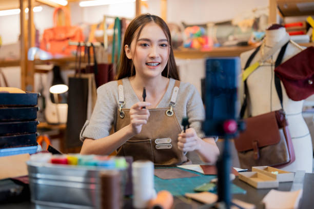 Leather bag making online course, asian female craft person influencer teaching how to make leather work bag online ,she is talking to student on smartphone lives online course