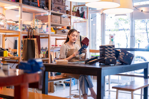 istock Leather studio craftman asian artisan working with leather bags part while gluing piece bag handle,The process of gluing leather tanned leather craft materials by a craftsman 2170380035