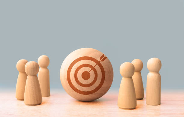 istock Wooden figures standing around dartboard and arrow for creative and set up business objective target goal, marketing solution 2170380073