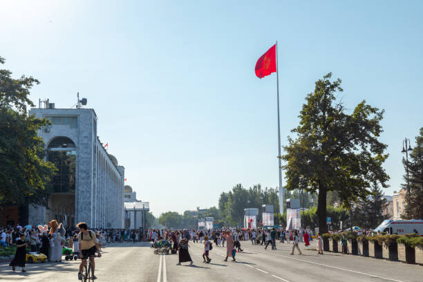 Bishkek, Kyrgyzstan - August 31, 2024: A crowd gathers on Central Square with people walking, national flag waving, and an ambulance parked during the celebration of Kyrgyzstan's Independence Day