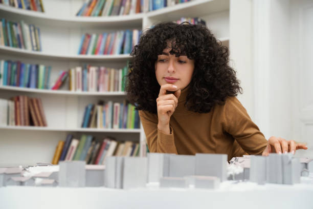 istock Curly-haired young woman sitting at the table and working on a layout 2170384007