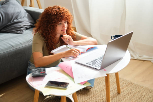 istock Focused young woman working from home is calculating domestic bills using laptop 2170384070