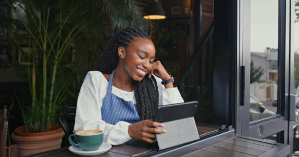 istock Black woman, waitress or coffee with tablet at cafe for online order, browsing or communication. Female person, young employee or hostess on technology by window for reservation service at restaurant 2170384422
