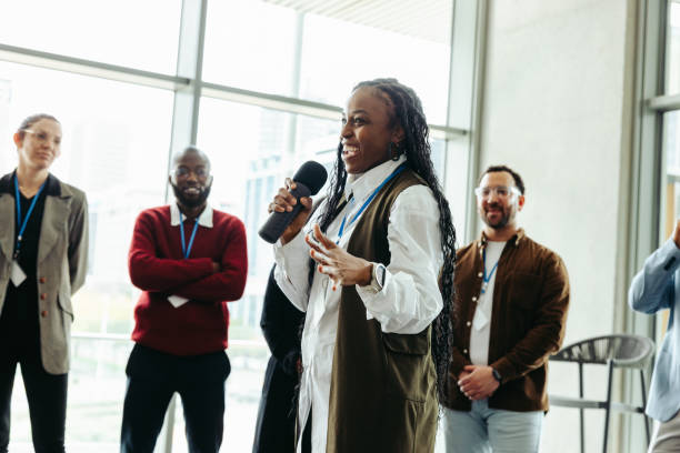 Confident woman speaking at a conference with colleagues in a modern office. Presenting ideas to engaged and diverse coworkers.
