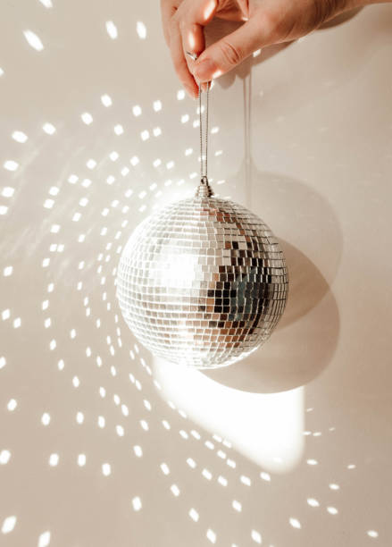 istock Close-up of a hand holding a disco ball, casting reflections and light patterns on the background 2170384985