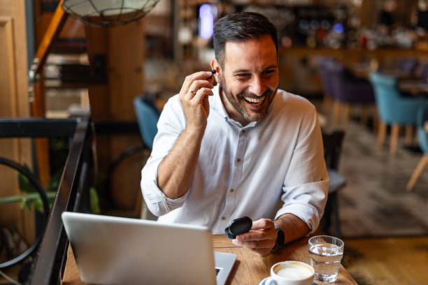 istock Satisfied modern business man in stylish clothes sitting in cafe using smartphone and headphones 2170385464