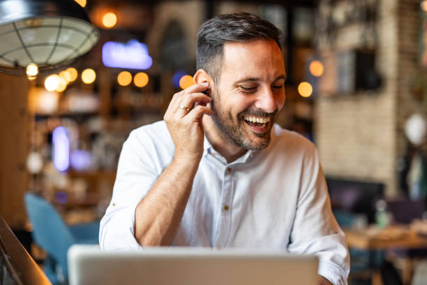 istock Satisfied modern business man in stylish clothes sitting in cafe using smartphone and headphones 2170385484