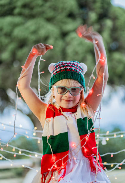Little blonde latina girl sitting playing with christmas lights and smiling happily