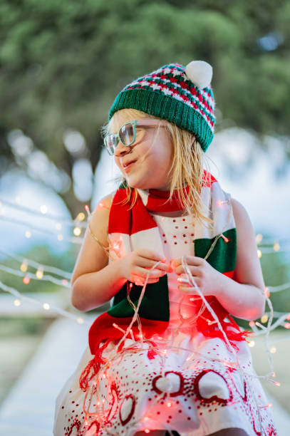 Portrait of a blonde girl looking to the side smiling and playing with Christmas lights