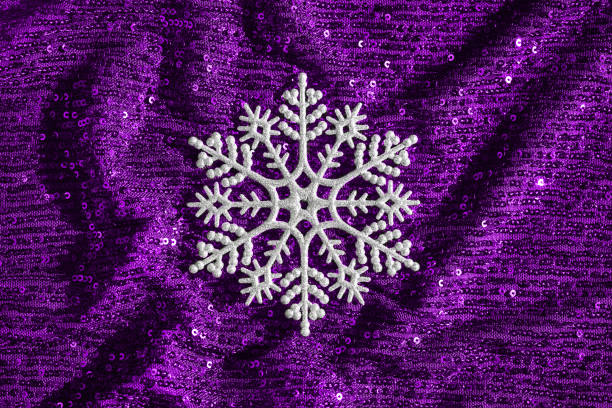 Abstract composition made of silver snowflake on shimmering purple background with sequins. Christmas and new year celebration concept