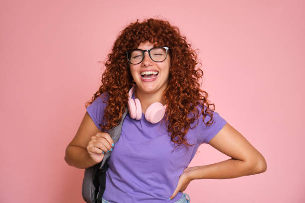 istock Carefree student with backpack and headphones laughing on pink background 2170389220