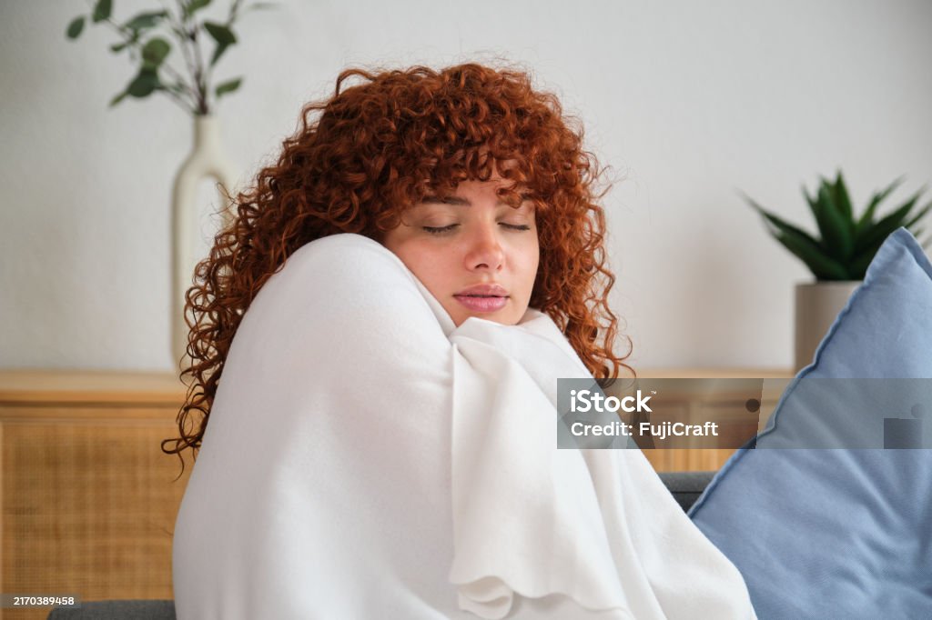 Fiatal nő takaróba burkolózva, rosszul érzi magát otthon a kanapén ülve - Jogdíjmentes 20-24 éves témájú stock fotó Fiatal nő takaróba burkolózva, rosszul érzi magát otthon a kanapén ülve - Jogdíjmentes 20-24 éves témájú stock fotó