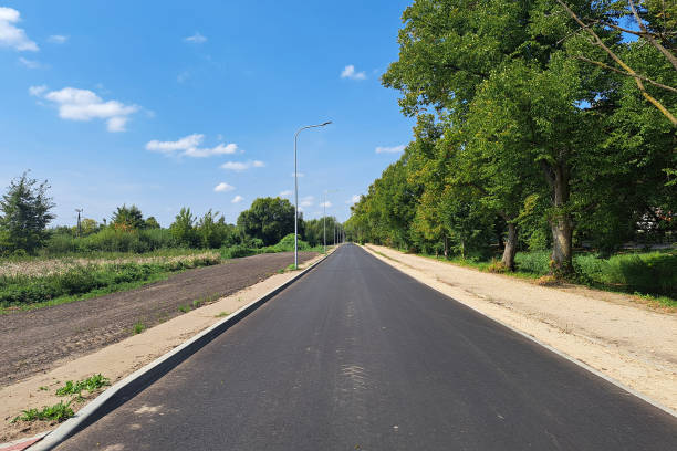 Newly built empty asphalt road, freshly paved and smooth, stretching through a quiet landscape, ideal for travel, transportation, and construction themes.
