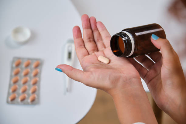 istock Sick unrecognizable woman taking pills from a bottle into hand 2170390033