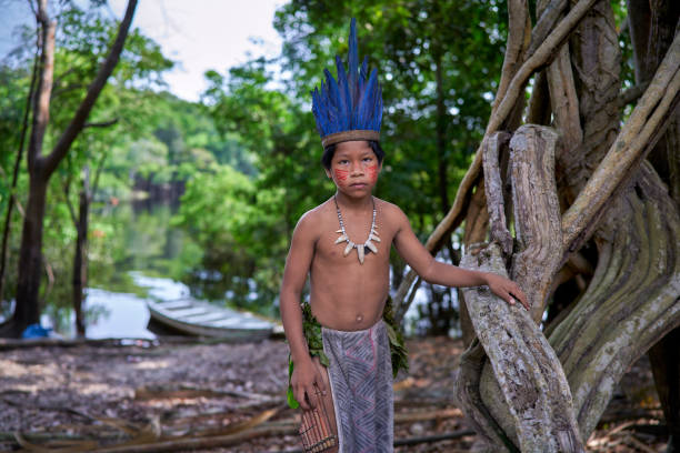istock A boy from an Amazon tribe in Brazil with his harmonica in the jungle with the river and canoes in the background 2170390184