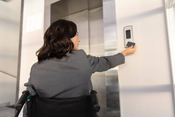 istock Woman in wheelchair working in her office and using elevator pushing button to get upstairs 2170390510