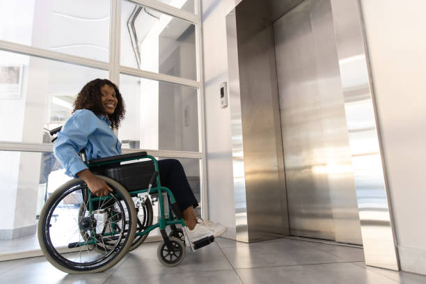 istock Female entrepreneur with disabilities in wheel chair waiting for elevator in office at work 2170390596